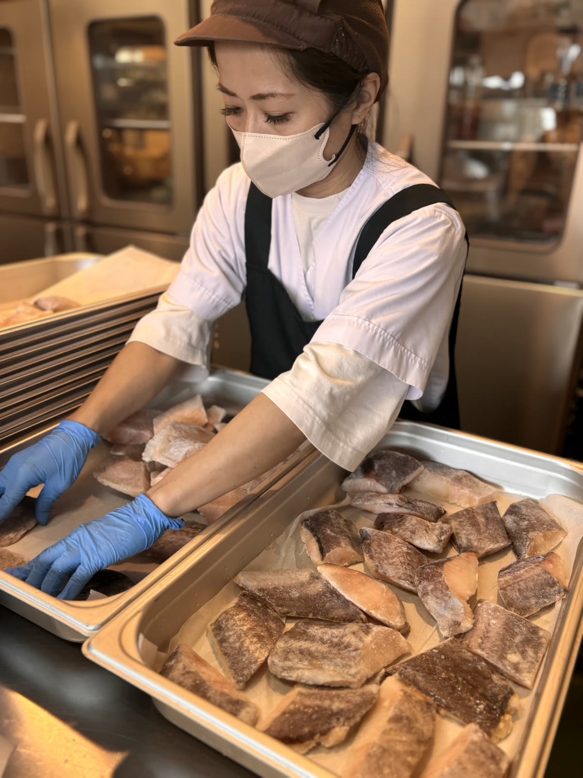 魚の切り身をバットに並べる調理スタッフ
